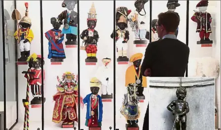  ??  ?? Clothes maketh the Manneken: A visitor looking at the historical collection of outfits created for the Manneken Pis statue (inset) at the Manneken Pis Wardrobe Museum in Brussels. — AFP