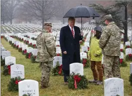  ?? CAROLYN KASTER — THE ASSOCIATED PRESS ?? President Donald Trump pauses in the rain among holiday wreaths at graves at Arlington National Cemetery in Arlington, Virginia, on Saturday.