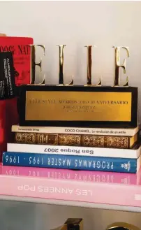  ??  ?? LECCIÓN DE ESTILO Arriba, detalle de la biblioteca, con el trofeo al mejor diseñador español de 2016 concedido por ELLE. Abajo, bajoplatos y jarra de la platería Arturo, vajilla en blanco y oro de porcelana de Limoges y platos verdes de San Claudio.