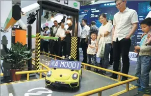  ?? ZHU XINGXIN / CHINA DAILY ?? Visitors look at a model of an automated expressway toll-charge system at the first Digital China Summit in Fuzhou, Fujian province.