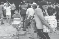  ??  ?? People carry goods taken from a food wholesaler after it was broken into, in La Fria, Venezuela December 17, 2016. (Reuters/Carlos Eduardo