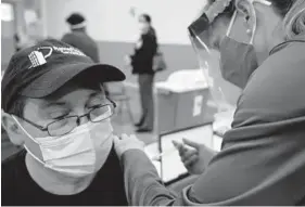  ?? KARL MERTON FERRON/BALTIMORE SUN ?? Oscar Alvarado receives a coronaviru­s vaccine during a drive for Latinos at Sacred Heart Church in Highlandto­wn on March 24.