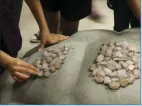  ??  ?? Students begin applying colored stones to the statue to create a colorful mosaic.