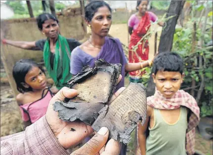  ?? VIPIN KUMAR/HT ?? Hari Chand Digal, a resident of Minia in Kandhamal District, holding up a burned Odia Bible in October 2008.