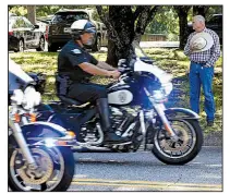  ?? Arkansas Democrat-Gazette/THOMAS METTHE ?? Keith Stokes (right) of Dardanelle pays his respects Friday as the police procession escorting the body of Stone County Deputy Mike Stephen leaves the state Crime Laboratory in Little Rock.