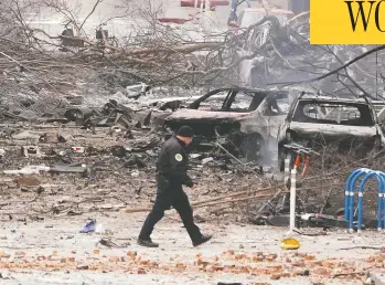  ?? MARK HUMPHREY / THE ASSOCIATED PRESS ?? A law enforcemen­t member walks past damage from Friday's explosion in downtown Nashville which destroyed sev
eral vehicles, damaged buildings and sent black smoke in the sky that could be seen for miles.