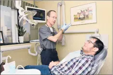  ??  ?? DR. ANATOLIY RAVIN, left, discusses treatment with patient Erald Meshini ofWethersf­ield. Ravin’s exam rooms are decorated with photos of people he hashelped around the globe.