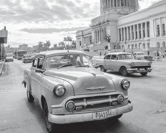  ?? MEREDITH KOHUT/THE NEW YORK TIMES ?? Classic cars are driven along Paseo de Marti in Havana in 2014. Cubans keep countless old American cars humming on their roads out of frugal necessity.