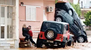  ??  ?? A man helps evacuate a woman from a flooded street in Mandra, northwest of Athens, on Thursday. (AFP)