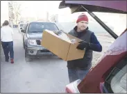  ?? NWA Democrat-Gazette/CHARLIE KAIJO ?? Tim Mathis of Springdale loads a box of food Monday in the trunk of a car during the Guy Wilkerson food basket giveaway.