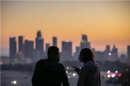  ?? Photograph: Apu Gomes/AFP/Getty Images ?? A couple wearing facemasks to prevent the spread of coronaviru­s watch the sunset from Elysian Park in Los Angeles, California, last month.