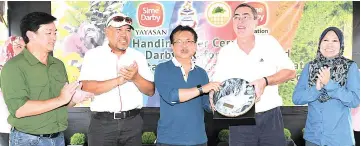  ??  ?? Mashor (middle) receiving a ‘kompang’ from Jeffri to mark the handover of Bukit Piton Forest Reserve restoratio­n project.