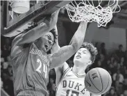  ?? Gerry Broome / Associated Press ?? Louisville’s Dwayne Sutton, left, dunks while Duke’s Alex O'Connell defends during Saturday’s game.