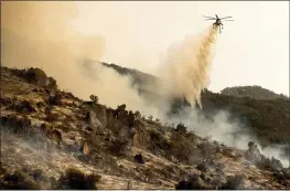  ?? NOAH BERGER — THE ASSOCIATED PRESS ?? A helicopter drops water on the KNP Complex Fire burning along Generals Highway in Sequoia National Park on Wednesday. The blaze is burning near the Giant Forest, home to more than 2,000 giant sequoias.