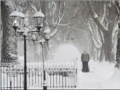  ?? DON CAMPBELL — THE HERALD-PALLADIUM VIA AP ?? A man clears snow along a sidewalk on State Street in St. Joseph, Mich., on Monday as storms blasted the area.