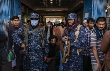  ?? (The New York Times/Victor J. Blue) ?? Taliban fighters guard the entrance to the Sarai Shahzada currency exchange Saturday in Kabul, Afghanista­n. Traders bemoaned the country’s faltering economy as cash supplies dwindle and government workers, unable to reach their offices, go unpaid.