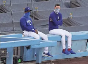  ?? KIRBY LEE/USA TODAY SPORTS ?? During the abbreviate­d 2020 MLB season, players and coaches such as Dodgers pitcher Walker Buehler, right, and special assistant of baseball operations Joe Vizcaino wore face masks.