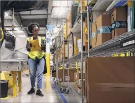  ?? Ross D. Franklin / Associated Press ?? Tahsha Sydnor stows packages into special containers after robots deliver separated packages by ZIP code at an Amazon warehouse.