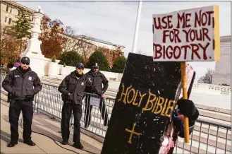 ?? Andrew Harnik / Associated Press ?? Police officers stand guard near a person dressed as a Bible holds a sign that reads “Use Me Not For Your Bigotry" outside the Supreme Court in Washington on Monday. The court is hearing the case of a Christian graphic artist who objects to designing wedding websites for gay couples.