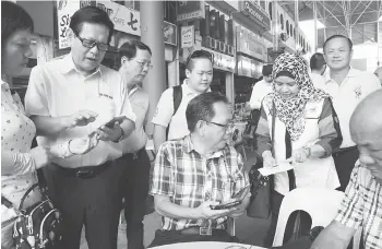  ??  ?? Sharifah Bahiyah helps a senior citizen connect to the WiFi. Lee is at second left.
