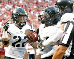  ?? AP Photo/Sue Ogrocki ?? ■ Army quarterbac­k Kelvin Hopkins Jr., center, celebrates with teammates Calen Holt (22) and Camden Harrison, right, after scoring against Oklahoma on Sept. 22 in Norman, Okla. Major college football teams are on a record scoring pace, and a more aggressive approach on fourth down is helping to fuel the surge. Army is the king of fourth down. The Black Knights have gone for it 48 percent of the time and converted 88 percent (22 for 25).