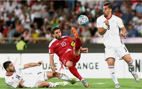  ??  ?? Can’t touch this: Syria’s Firas Mohamad Alkhatib vying for the ball with Iran’s Ehsan Hajsafi (right) and Ali Karimi during their World Cup Asian qualifying Group A match at the Azadi Stadium in Teheran on Tuesday.