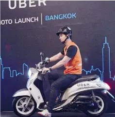  ??  ?? A man drives a motorbike onto a stage during the launch of UberMOTO at a hotel in Bangkok. — AFP photo