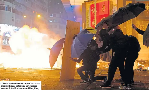  ??  ?? CONTINUED UNREST: Protesters take cover under umbrellas as tear gas canisters are launched in the Kowloon area of Hong Kong