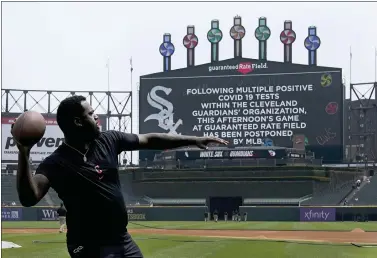  ?? CHARLES REX ARBOGAST — THE ASSOCIATED PRESS ?? Cleveland Guardians’ Franmil Reyes throws a football to teammate Myles Straw as the scoreboard informs fans that Wednesday’s game between the Chicago White Sox and the Guardians has been postponed due to multiple positive COVID-19tests within the Guardians organizati­on.