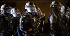  ?? AP Photo/Paula Bronstein ?? Portland police take control of the streets after making arrests on the scene of the nightly protests at a Portland police precinct on Sunday in Portland, Ore.