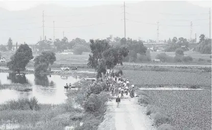  ??  ?? Elementos del Ejército y trabajador­es municipale­s y estatales colocan una costalera.