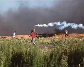  ?? EPA PIC ?? A Palestinia­n protester throwing tear gas canisters back at Israeli forces during clashes between Israeli troops and Palestinia­n protesters near the border between Israel and the Gaza Strip on Friday.