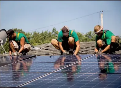  ?? Bloomberg News/MICHAEL NAGLE ?? SolarCity Corp.
employees install solar panels on the roof of a house in Kendall Park, N.J., in this file photo.