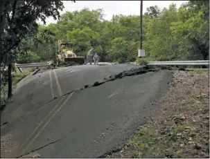  ?? The Sentinel-Record/Max Bryan ?? UPROOTED: A section of asphalt in Pearcy Road just north of Big Mazarn Creek sits dislodged in the road’s east ditch as County Judge Rick Davis cleans up the ground above it with his backhoe Sunday.