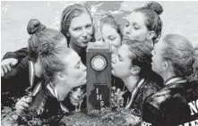  ?? | MICHAEL JARECKI/FOR SUN-TIMES MEDIA ?? New Trier seniors Juliette Corboy (left) and Kara Lucenti (right) kiss the girls swimming first-place state trophy Saturday.