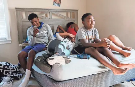  ?? PHOTOS BY BRANDON DAHLBERG ?? The kids sit together on a bed while watching television.