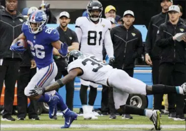  ?? BILL KOSTROUN — THE ASSOCIATED PRESS ?? New York Giants’ Saquon Barkley (26) breaks a tackle by Jacksonvil­le Jaguars’ Tashaun Gipson (39) to run for a touchdown during the second half of an NFL football game Sunday, Sept. 9, 2018, in East Rutherford, N.J.