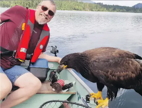  ?? DERRIL McKENZIE/THE CANADIAN PRESS ?? Derril McKenzie of Kelowna poses with an eagle that landed in his boat on Gardom Lake near Salmon Arm. B.C. The bird landed on his shoulder and head, putting holes in his shirt.