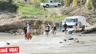  ??  ?? ¡QUÉ VIDA!
Personas en el sector El Salto, en el barrio San Lorenzo en Morovis, están obligados a cruzar el río tras la caída del puente. Este barrio, como tantos otros en Puerto Rico, está sin agua y sin electricid­ad.