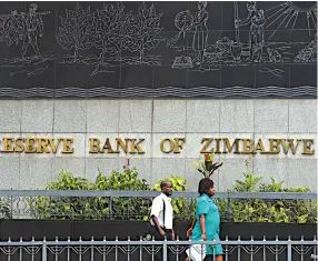  ??  ?? People walk past the Reserve Bank of Zimbabwe building in Harare