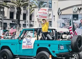  ?? Allen J. Schaben Los Angeles Times ?? ANOTHER Huntington Beach expression of opposition to the state’s public health mandates. Elsewhere in O.C., hundreds of people burned their masks at a San Clemente beachside bonfire.