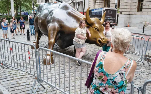  ?? Agence France-presse ?? ±
People pose with the Wall Street bull in the financial district of New York on Monday.