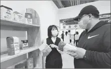  ?? PHOTOS BY SHAO GUOLIANG / FOR CHINA DAILY ?? Top: The free trade zone market in Suifenhe, Heilongjia­ng province. Above: A staff member at the market introduces a pack of Russian flour to a customer.