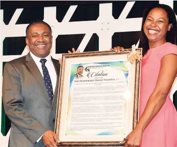  ??  ?? Former government minister Phillip Paulwell accepts the citation in his honour from manager, strategic initiative­s, Sutherland Global Services, and BPIAJ board member Olivia Leigh Campbell. Paulwell was recognised for his outstandin­g work in the...