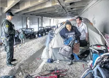  ?? Irfan Khan ?? LOS ANGELES COUNTY Sheriff’s Deputy Michael Galvan, left, warns a couple living under the 5 Freeway near the San Gabriel River in Pico Rivera about the dangers of f looding from rainstorms.