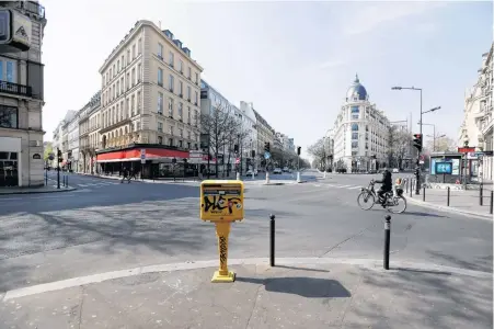  ?? REUTERS/FILE ?? A cyclist rides on the deserted Grands Boulevards in Paris as a lockdown is imposed to slow the rate of the coronaviru­s disease (COVID-19) in France, March 27.