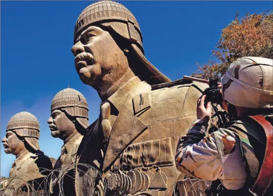  ?? AHMAD AL-RUBAYE ?? Some of the last remaining statues of ousted Iraqi dictator Saddam Hussein overlook Baghdad’s heavily fortified Green Zone, where Saddam is to appear in court today.