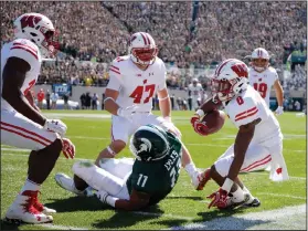  ?? AP PHOTO ?? Wisconsin’s Sojourn Shelton, right, Vince Biegel (47) and Leon Jacobs, left, celebrate Shelton’s intercepti­on against Michigan State’s Jamal Lyles (11).