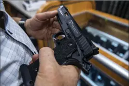  ?? BRITTAINY NEWMAN — THE ASSOCIATED PRESS FILE ?? A customer checks out a gun for sale at a firearms store in Hempstead, New York. The Supreme Court's so-called Bruen decision changed the test that lower courts had long used for evaluating challenges to firearm restrictio­ns.