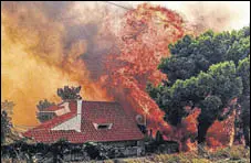  ?? AFP ?? A house is engulfed by a huge blaze during a wildfire in Kineta, near Athens, on Monday.